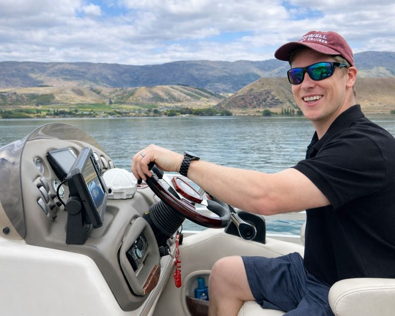 Cromwell Winery Cruises boat tour with scenic views of vineyards and water, featuring a captain at the helm.