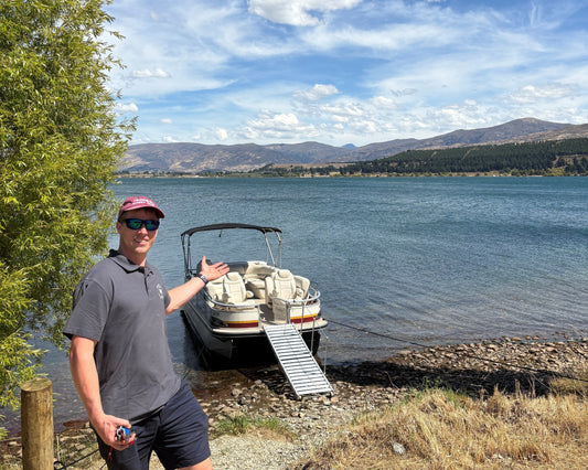 Half day tour boat cruising through scenic vineyards with passengers enjoying the views at Cromwell Winery Cruises.