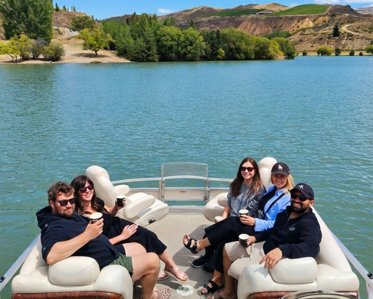 Group of people enjoying a sunny boat tour with Cromwell Winery Cruises on a scenic waterway.